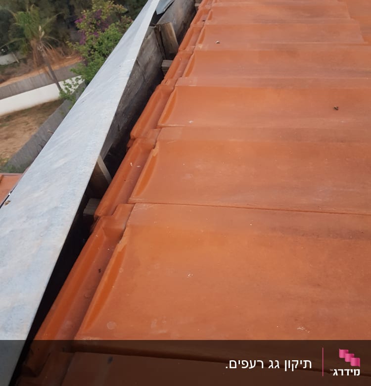 רעפים כתומים על גג עם פח מתכת בצד